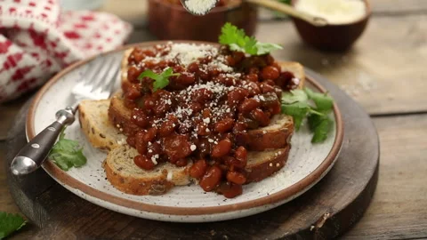 Baked beans on toast with cilantro, adding cheese on top Stock Footage 242534202