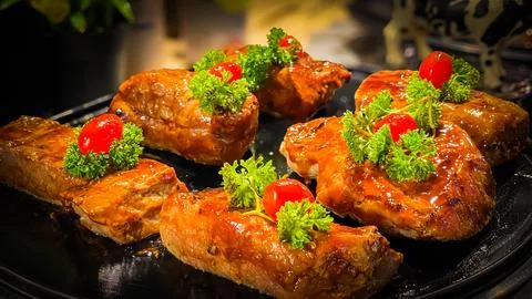Baked beef with herbs and cherry tomatoes on a serving platter Stock Photos