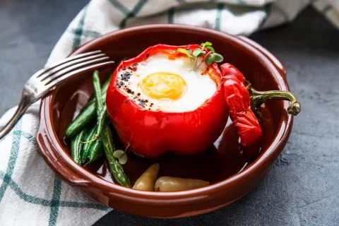 Baked bell pepper stuffed with egg and sausage on a plate, dark Stock Photos