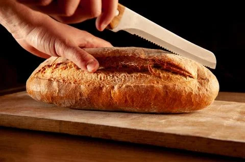 Baked bread is cut with a knife Fotos Stock