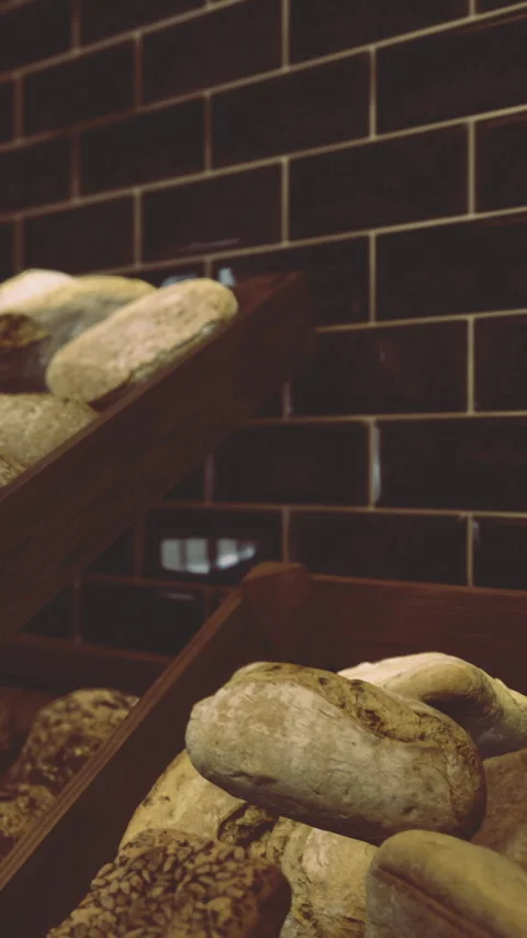Baked bread displayed in a bakery with dark tiled walls at morning time 스톡 동영상 331662364