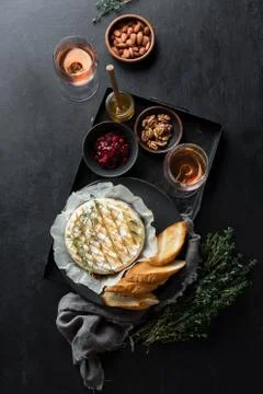 Baked brie served in a rustic manner with honey walnuts cranberry jam and ros Stock Photos