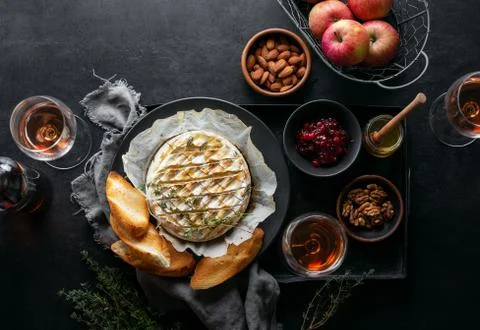 Baked brie served in a rustic manner with honey walnuts cranberry jam and ros Stock Photos