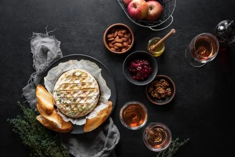 Baked brie served in a rustic manner with honey walnuts cranberry jam and ros Stock Photos
