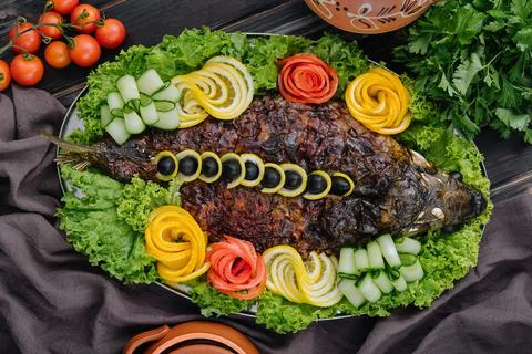 Baked carp with vegetables close-up in a baking dish on the table Stock Photos