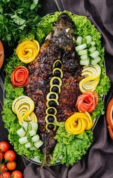 Baked carp with vegetables close-up in a baking dish on the table Stock Photos