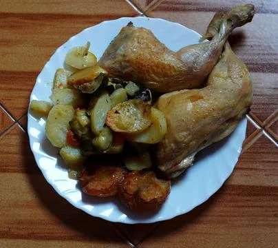 Baked chicken legs lie in a white plate Stock Photos