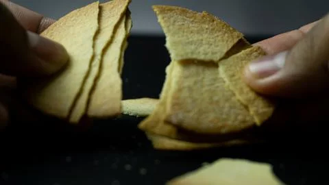 Baked chips being broken by hand on a black background table Stock Photos