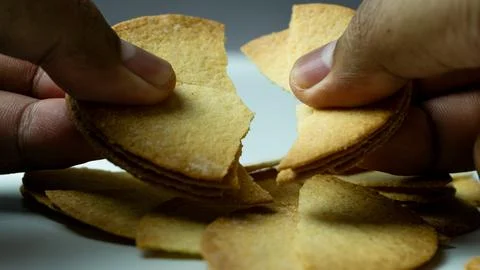 Baked chips being broken by hand on a white background table Stock Photos