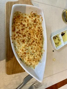 Baked cod dish on a white platter in the shape of a boat Stock Photos