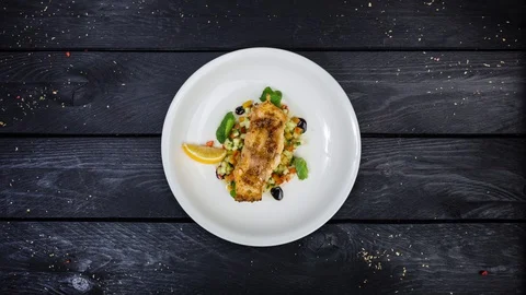 Baked cod fillet with vegetables rotating on white plate. Stock Footage 128708256