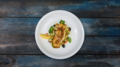Baked cod fillet with vegetables rotating on white plate. Stock Footage 128708344