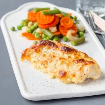 Baked cod fish fillet under cheese, mustard, pepper and cream crust 스톡 사진