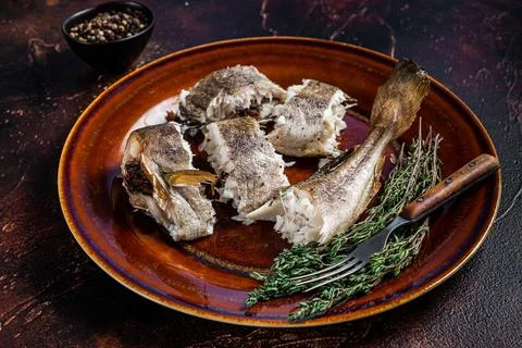 Baked cod white fish in a plate. Dark wooden background. Top view Stock Photos