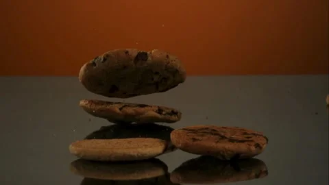 Baked cookies falling and bouncing on a reflective table Stock Footage 327786903