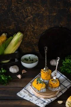 Baked corn with spiced butter on a rustic wooden background. Barbecue food. T Stock Photos