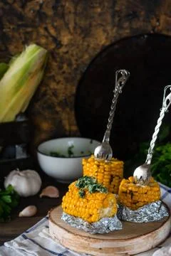 Baked corn with spiced butter on a rustic wooden background. Barbecue food. T Stock Photos