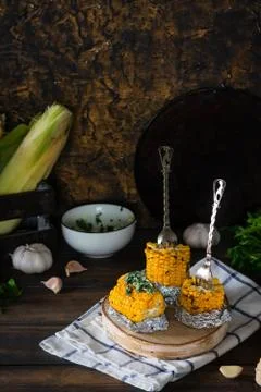 Baked corn with spiced butter on a rustic wooden background. Barbecue food. T Stock Photos