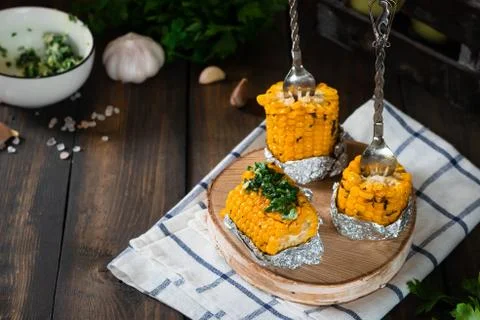 Baked corn with spiced butter on a rustic wooden background. Barbecue food. T Stock Photos