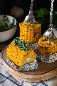 Baked corn with spiced butter on a rustic wooden background. Barbecue food. T Stock Photos