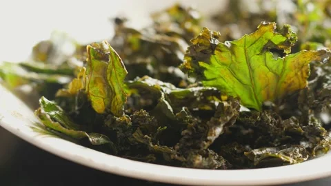 Baked curly kale chips crispy dry dried leaves rotating turning round Stock Footage 137693696