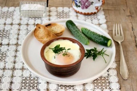 Baked egg with bread and cucumber. Rustic style, selective focus. Stock Photos