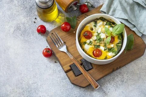Baked egg omelette with spinach, cherry tomato and feta cheese on a stone s.. Fotos de archivo