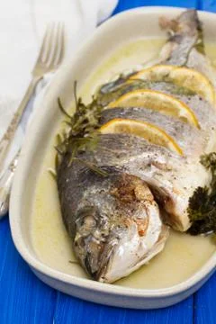 Baked fish with lemon on dish Stock Photos