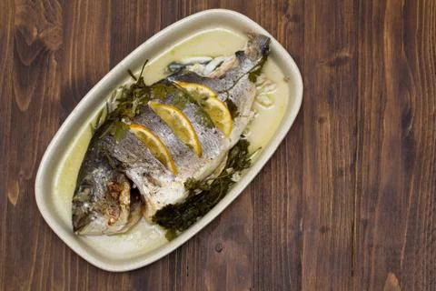 Baked fish with lemon on dish Stock Photos