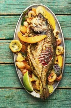 Baked fish with pineapple, mango and kiwi. Stock Photos