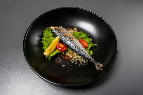 Baked fish without head with tomatoes, lettuce, microgreens, spices  Stock Photos