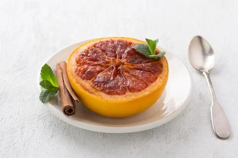 Baked grapefruit with brown sugar and cinnamon garnished with mint on a lig.. Stock Photos