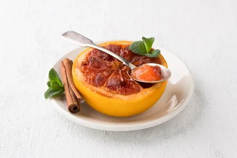 Baked grapefruit with brown sugar and cinnamon garnished with mint on a lig.. Stock Photos