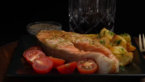 Baked large piece of trout steak with tomatoes and potatoes on plate, rotates Stock Footage 295966463