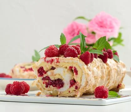 Baked meringue roll with cream and fresh red raspberry, white background Stock Photos