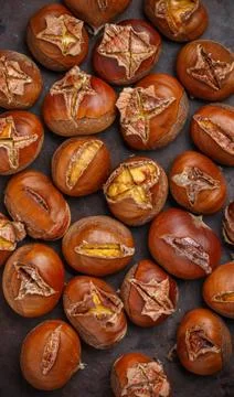 Baked or fried chestnuts in a shell on a metal baking sheet. A delicious a... Stock-Fotos