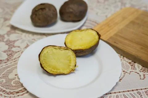Baked potatoes cut into halves on the table Stock Photos