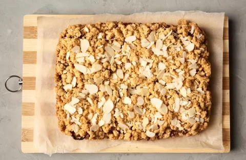Baked rectangular crumble cake with fruit filling on wooden board, gray backg Stock Photos