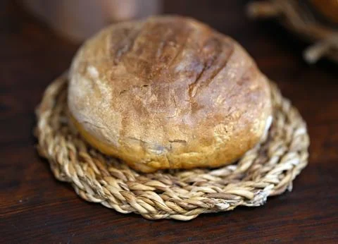 Baked round bread on a wicker straw stand Stock Photos