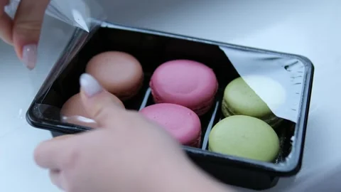Baked round multi-colored macarons in cardboard box, female hands take dessert Stock Footage 302103276