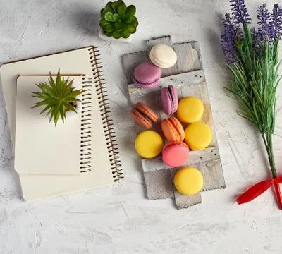 Baked round multi-colored macarons on a wooden board, stack of spiral noteboo Stockfoto's