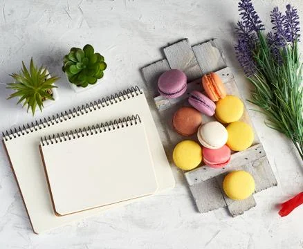 Baked round multi-colored macarons on a wooden board, stack of spiral noteboo Stock Photos