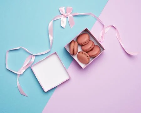 Baked round multicolored macarons in square boxes on a colored pastel backgro Stock Photos