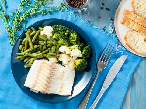 Baked sea fish cod fillet with vegetables - broccoli, green beans and Stock Photos