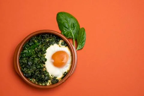Baked spinach and egg in a clay pot. Flat lay image Stock Photos
