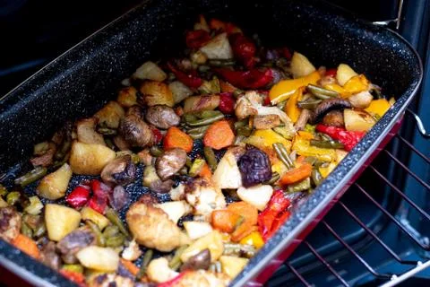 Baked vegetables on a red baking sheet..Vegetable stew on a baking sheet in t Stock Photos