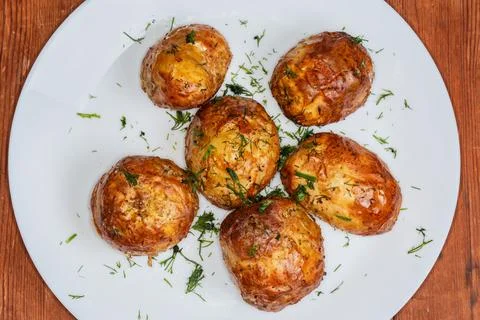 Baked young potatoes on dish on rustic table, top view Stock Photos