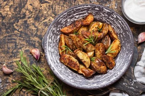 Baked young potatoes in a rustic style with sour cream Stock Photos
