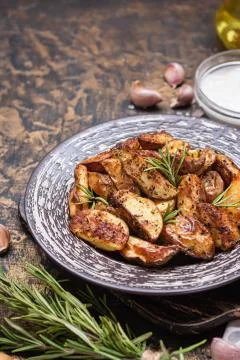 Baked young potatoes in a rustic style with sour cream Stock Photos