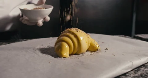 Baker adding 5 cereal topping to croissant Stock Footage 171175177